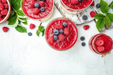 Küçük kavanozlarda hafif arka planda krema soslu böğürtlenli tatlı. Uzun afiş biçimi. metin için yer.