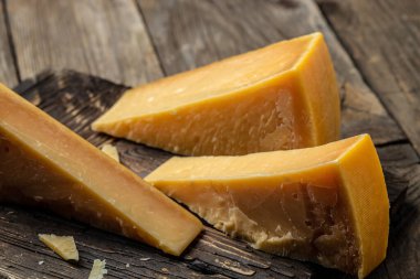 Parmesan peyniri dilimlenmiş ve rendelenmiş. Tahta arka planda bıçaklı bir parmesan peyniri seti. en üstteki görünüm.