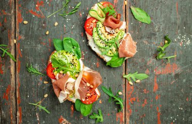 Open sandwich with prosciutto or jamon, avocado and fresh greens. Keto breakfast or snack, top view.