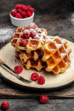 Belgian waffles with raspberries with sugar powder in a freeze motion of a cloud of powder midair, served with jug of milk. Delicious breakfast or snack. vertical image. top view. place for text,