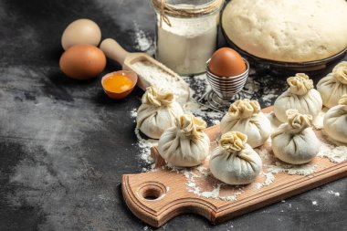 Raw Khinkali with meat on a wooden board. semi-finished products dumplings cooking khinkali on a dark background. Georgian dumplings.