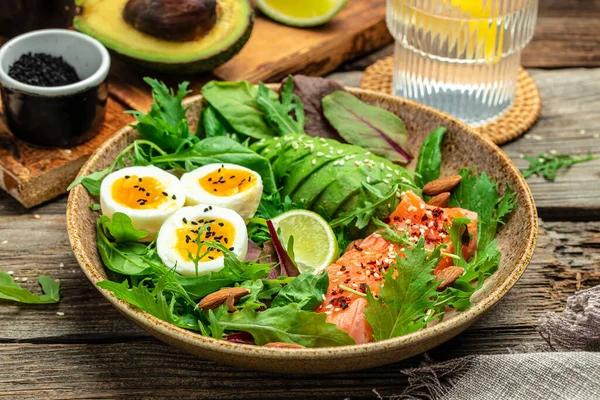 stock image Keto bowl salmon salad with greens, eggs and avocado. Ketogenic diet breakfast lunch. Top view.