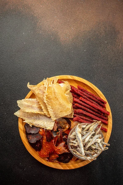variety of dried fish, snacks for beer on a dark background. vertical image. top view. place for text.