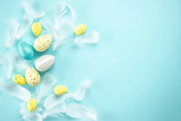 Easter background with Easter eggs with feathers on a blue background. Happy Easter holiday concept.