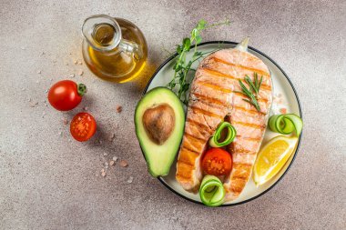 Avokado ve taze sebze salatasıyla ızgara somon bifteği. Keto diyet konsepti sağlıklı yiyecekler, sağlıklı yağlar, kilo vermek için temiz yiyecekler. en üstteki görünüm.