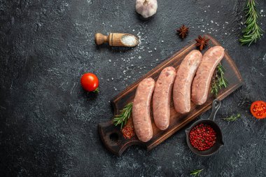 Tahtada çiğ sosis, baharatlar, domatesler ve bitkilerle. afiş, menü, metin için tarif yeri, üst görünüm.