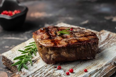 grilled beef steaks with spices on a wooden board. Restaurant menu, dieting, cookbook recipe top view.
