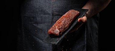 Şefin elleri et pişiriyor ve baharat ekliyor taze çiğ çiğ Angus bifteği. Et pişirme kavramı,