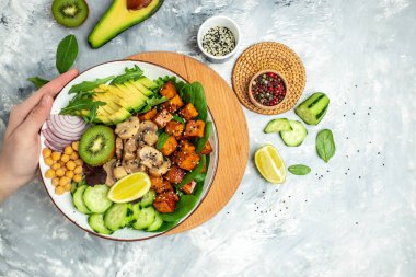 Healthy vegetable lunch in a Buddha bowl with tofu, avocado, chickpeas, cucumber and mushrooms, banner, menu, recipe place for text, top view,