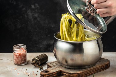 Kaynayan fettucine makarna. Tencereye tuz ve zeytinyağı koyan..