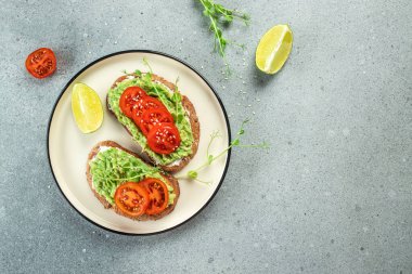 Avokado soslu sandviç ve açık arkaplanda domates. Vejetaryen yemeği. Vejetaryen menüsü. metin için yer, üst görünüm,