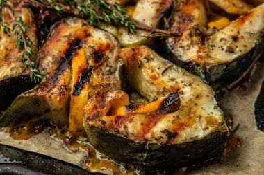 Sturgeon steaks on the grill with lemon herbs and spices. Food recipe background. Close up.