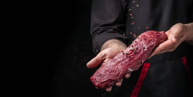 Biberiye ve baharatlı dondurulmuş biftekli şef tuzu. Karanlık bir arka planda taze et ya da domuz eti hazırlıyorum. Uzun pankart biçimi.