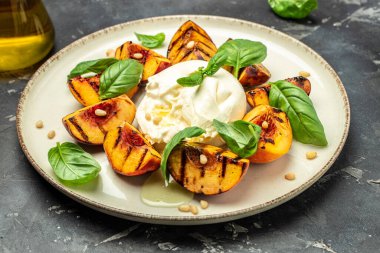 Gourmet Roasted Peaches with Burrata soft cheese, basil and drizzled with honey, with rose wine. Antipasto Dinner or aperitivo party.