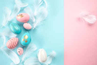 Paskalya süslemeleri tüyleri pembe ve beyaz paskalya yumurtalarını pastel mavi arka planda bırakır. Paskalya arkaplanı.