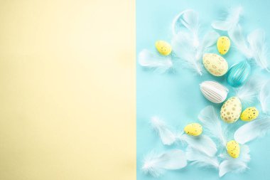 Paskalya arkaplanında mavi arka planda tüyleri olan Paskalya yumurtaları. Mutlu Paskalya tatili konsepti.