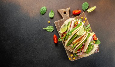 Dürümlü taco ızgara tavuk, avokado, taze domates, tahtadan yapılmış limon. Uzun afiş biçimi. en üstteki görünüm.