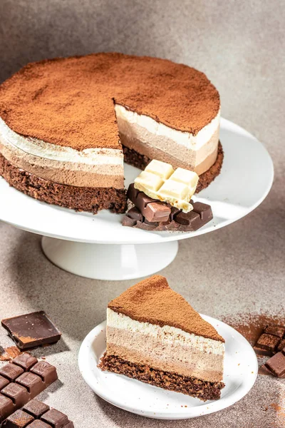 Three layered chocolate mousse cake on a light background. vertical image. top view. place for text.