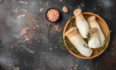 Fresh raw mushrooms, king oyster or eringi on a dark background, Long banner format. top view,