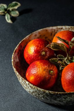 Gri arka planda kanlı Sicilya portakalları. Kesilmiş, yapraklarla yarıya bölünmüş, desenli. en üstteki görünüm.