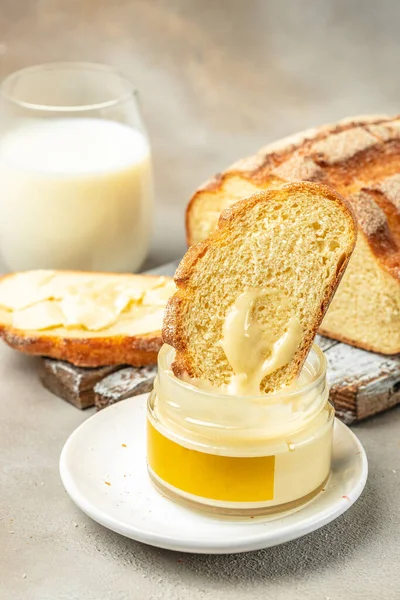 stock image glass of milk with, honey and bread on light background. breakfast food concept.