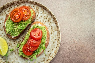 Avokado tostu ve açık arkaplanda domatesler. Vejetaryen yemeği. Vejetaryen menüsü. metin için yer, üst görünüm.
