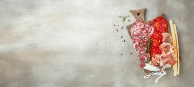 Geleneksel İspanyol mezelerinden yapılmış bir tabak et. Chorizo, Jamon Serrano, Lomo ve Fuet. Uzun afiş biçimi. en üstteki görünüm,