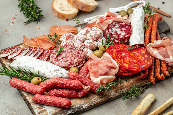Salami, sliced ham, sausage, prosciutto bacon, toasts, olives. Meat antipasto platter and red wine, Food recipe background. Close up,