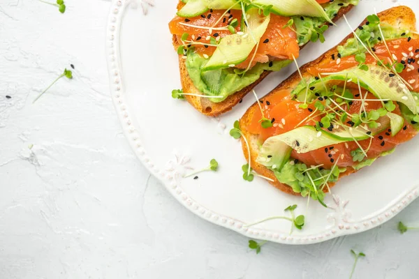 Krem peynirli sandviç, somon, avokado, salatalık, domates ve açık arkaplanda yeşillikler. Keto kahvaltısı ya da brunch. afiş, menü, metin için tarif yeri, üst görünüm.