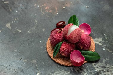 Sulu Lychee, ortadan ikiye bölünmüş ve tabakta koyu bir arka plan, üst görünüm bırakıyor..