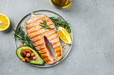 Avokado ve taze sebze salatasıyla ızgara somon bifteği. Keto diyet konsepti sağlıklı yiyecekler, sağlıklı yağlar, kilo vermek için temiz yiyecekler. en üstteki görünüm.