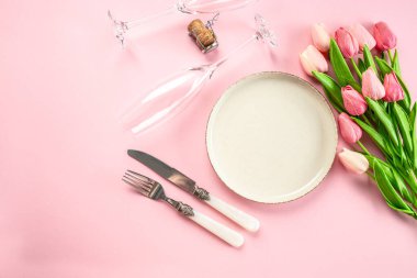 Şenlikli yaratıcı masa seti ve pembe arka planda lale buketi. Kadınlar Günü ve Anneler Günü.