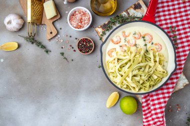 shrimps bechamel sauce in pan. pasta on a dark background. banner, menu, recipe place for text, top view.