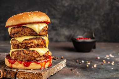 Çifte pirzola, duble çedar peyniri, sos ve el yapımı çörek. Fast food ve abur cubur kavramı.