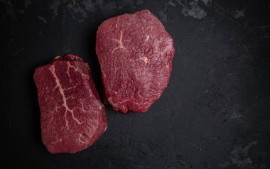 İki taze çiğ biftek ve arkaplanda pişmeye hazır baharatlar. Mutfak, yemek pişirme, konsept. afiş, menü, metin için tarif yeri, üst görünüm.