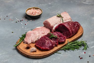 raw pork meat and beef with rosemary and spices on a wooden board. Restaurant menu, dieting, cookbook recipe. place for text.