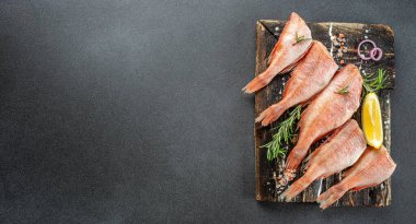 Limonlu çiğ balık levreği, biberiye, koyu arkaplanda tuz. Uzun afiş biçimi. en üstteki görünüm.