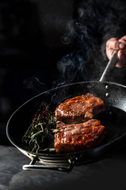 Izgara tavada sulu, lezzetli biftek ve koyu bir arka planda buhar. dikey görüntü. Üst Manzara. metin için yer.