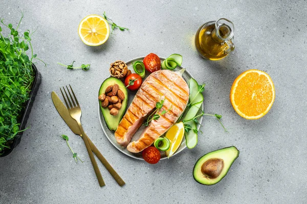 Grilled salmon steak with avocado and fresh vegetable salad. Keto diet, Healthy food concept. place for text, top view.