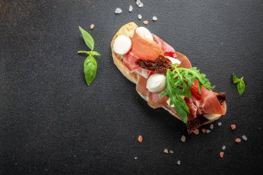 İspanyol Tapas 'ı, koyu arkaplanda fesleğenli jambon dilimleri ile birlikte. afiş, menü, metin için tarif yeri, üst görünüm.