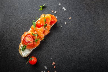 Somon ve krem peynirli, koyu arkaplanda lezzetli bir bruschetta. afiş, menü, metin için tarif yeri, üst görünüm.