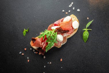 Esmer arka planda jambonlu lezzetli bruschetta. afiş, menü, metin için tarif yeri, üst görünüm.