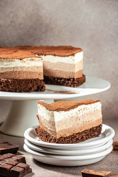 Three layered chocolate mousse cake on a light background. vertical image. top view. place for text.