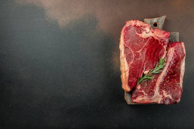 Siyah taşlı arka planda et bifteği ve bıçak arasında bir kemik. Çiğ et. metin için yer, üst görünüm.