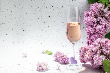 Hafif arka planda çiçek açan leylak rengi bir kadeh şampanya.,