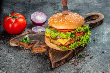 Sığır etli, domatesli, peynirli ve marullu taze ev yapımı burger. Fast food ve abur cubur kavramı.
