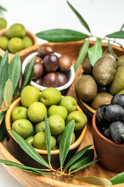 Yeşil zeytin, siyah zeytin ve kırmızı kama zeytinleri ve ekstra saf zeytin yağı, hafif arkaplanda zeytinlerden yapılmış ürünler. metin için yer, üst görünüm,