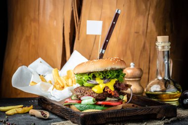 Ahşap arka planda pirzola ve pastırmalı büyük bir hamburger.,