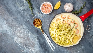 shrimps bechamel sauce in pan. pasta on a dark background. banner, menu, recipe place for text, top view.