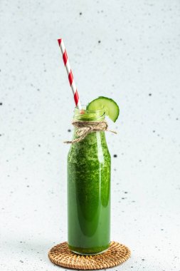 Hafif arka planda, dikey görüntüde, şişe içindeki yeşil smoothie 'yi detoks et. metin için yer,